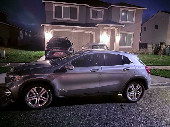 Silver SUV parked illegally blocking driveway at night in a suburban neighborhood, example of horrific neighbors shamed publicly.