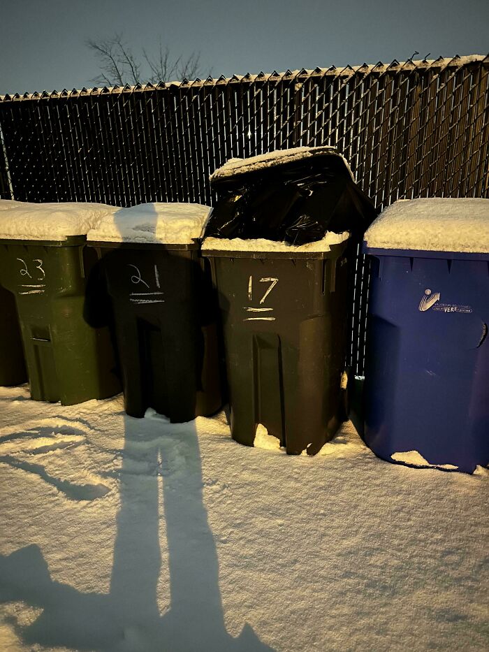 Overflowing trash bins in snowy alley, representing terrible neighbors.