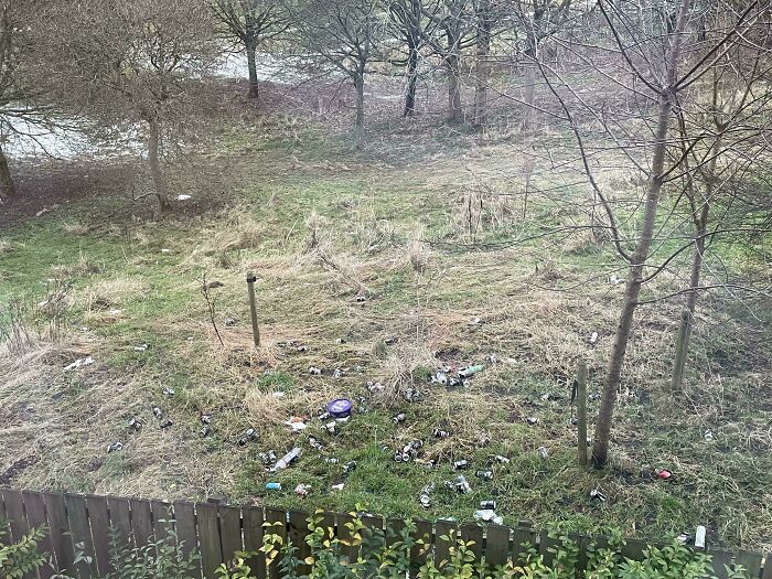 A yard littered with garbage behind a fence, showcasing terrible neighbors' impact on the environment.