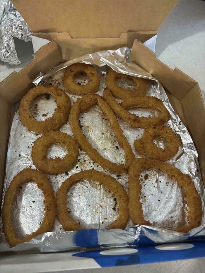 Fried onion rings arranged on foil inside a pizza box, reflecting an Australian community's surprising food arrangement.