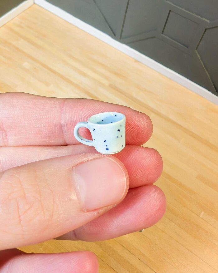 Close-up of a hand holding a tiny DIY miniature cup with speckled design.