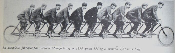 Eight men riding an 1898 Waltham Manufacturing decuplet bike, an historical invention ahead of its time.