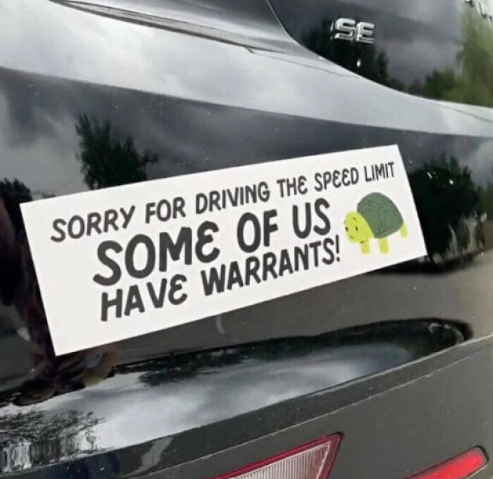 Funny bumper sticker on a car saying "Sorry for driving the speed limit, some of us have warrants!" with a turtle graphic.