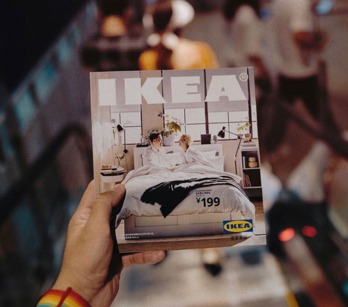 Hand holding an IKEA catalog while descending an escalator, focusing on the cover image.