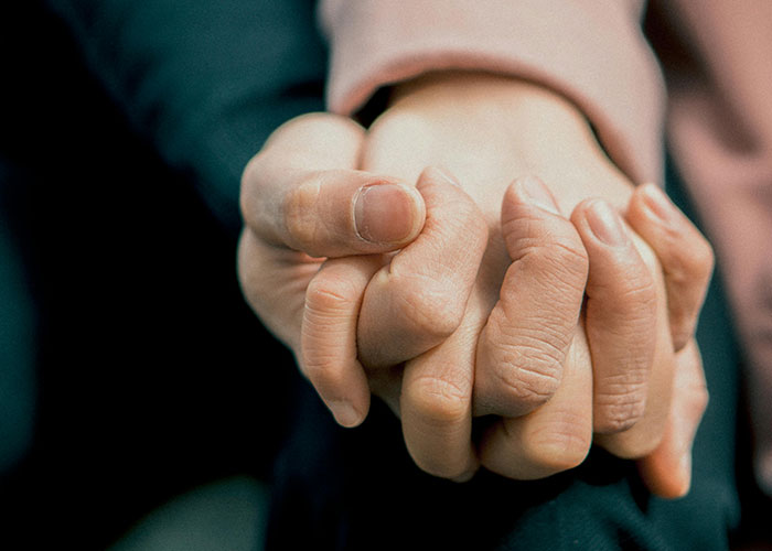 Two hands clasped gently, conveying a sense of connection and emotional depth.