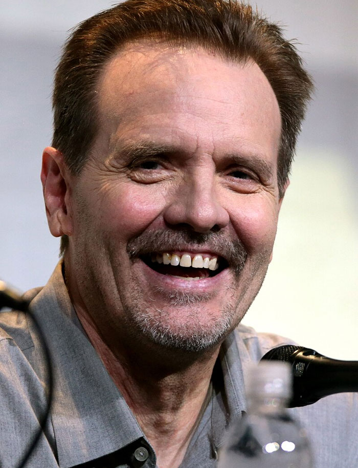 Smiling celebrity in a gray shirt at a public event, illustrating fame changes.