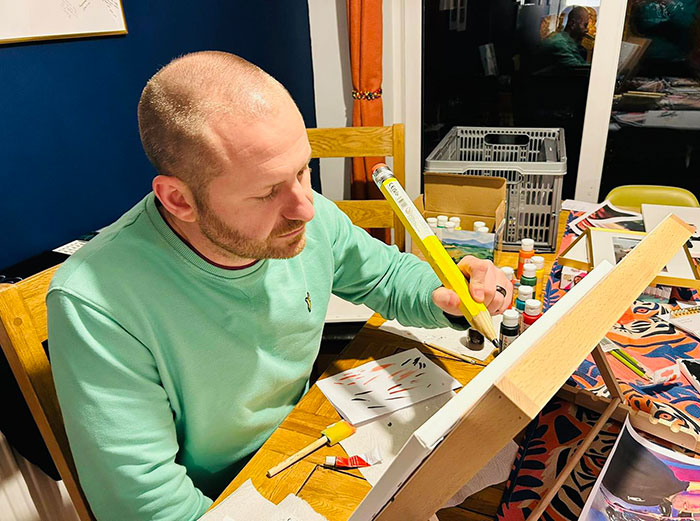 Man painting on canvas in a well-lit room, surrounded by art supplies, focusing on his work. Man painting on canvas in a well-lit room, surrounded by art supplies, focusing on his work.