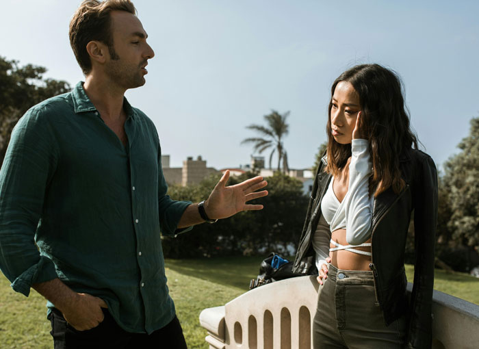 Young couple having a tense conversation in a park, relating to teenage relationship issues.