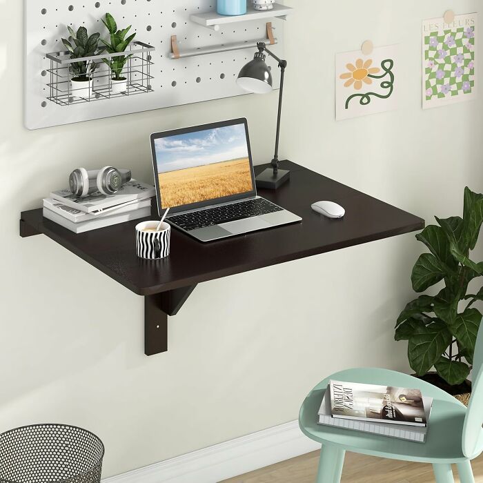 Wall-mounted desk with laptop and decor, showcasing smart furniture solutions for small living spaces.