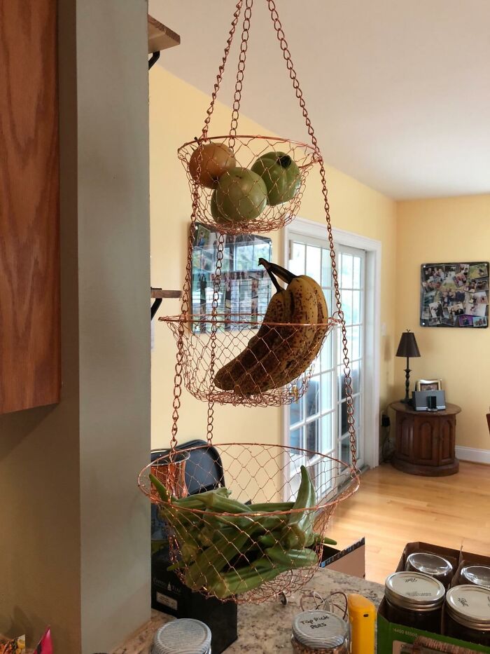 Hanging wire baskets in small kitchen, storing fruits and vegetables for clever space-saving design.