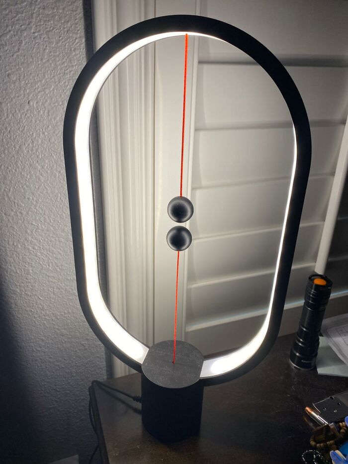 Modern tech find: an innovative lamp with a circular LED frame and magnetic floating balls for switch control.