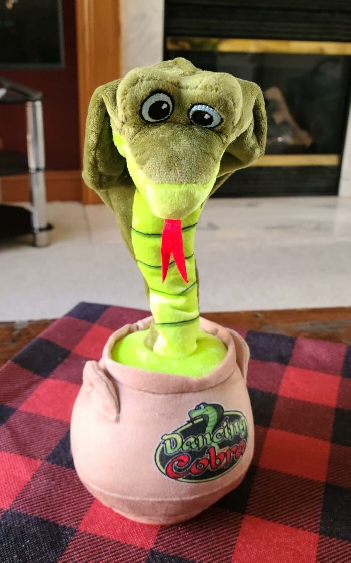A cute dancing cobra plush toy, a funniest Amazon find, displayed on a checkered tablecloth indoors.