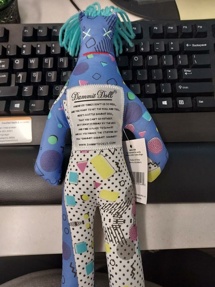 Colorful stress-relief doll with geometric patterns on an office keyboard, showcasing fun office supplies.