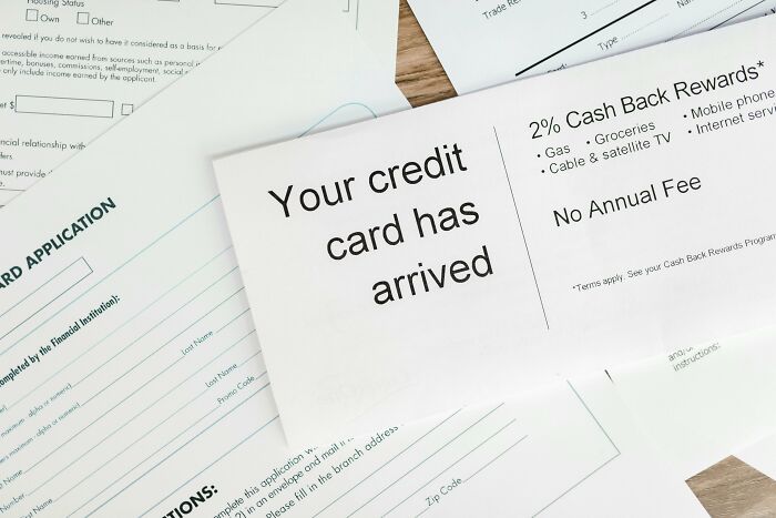 Credit card arrival notice among application forms, highlighting outdated financial stereotypes.
