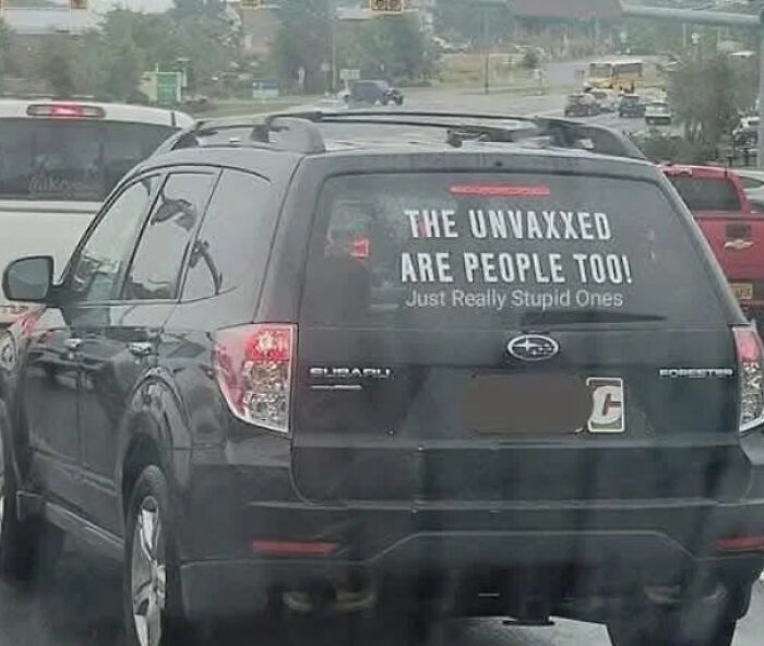 SUV with a funny bumper sticker about the unvaccinated at a traffic light.
