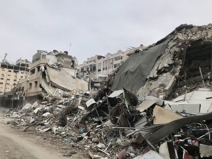 Collapsed buildings and rubble in a war-torn area showing destruction where people survived due to another’s sacrifice.