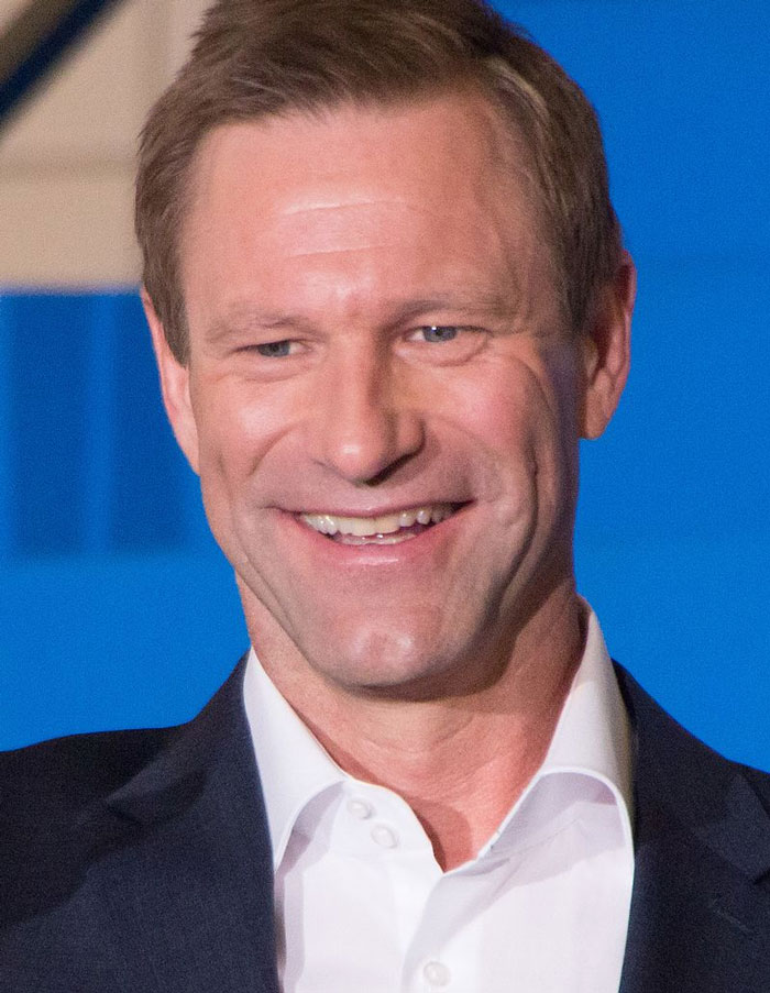 Smiling man in a suit at an event, representing celebrities with fading fame.