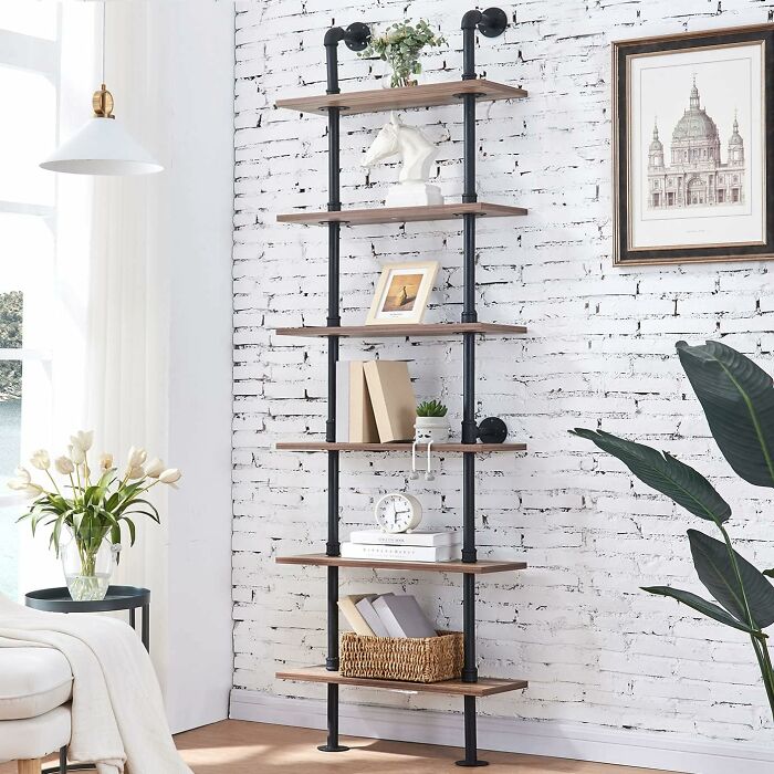 Vertical shelving unit against white brick wall, showcasing smart furniture solution for small living spaces.