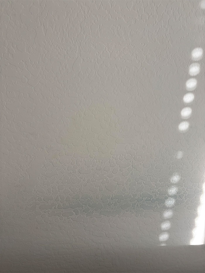 Wall with faint stains and dappled sunlight, related to online user comments about suspicions of a mistress's presence.