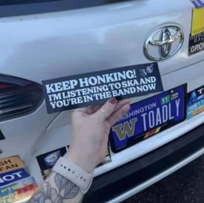 Funny bumper sticker on a car reads, "Keep honking! I'm listening to ska and you're in the band now."
