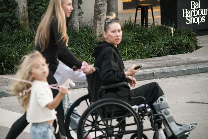 Tennis star in a wheelchair at Bal Harbour Shops, accompanied by two children.