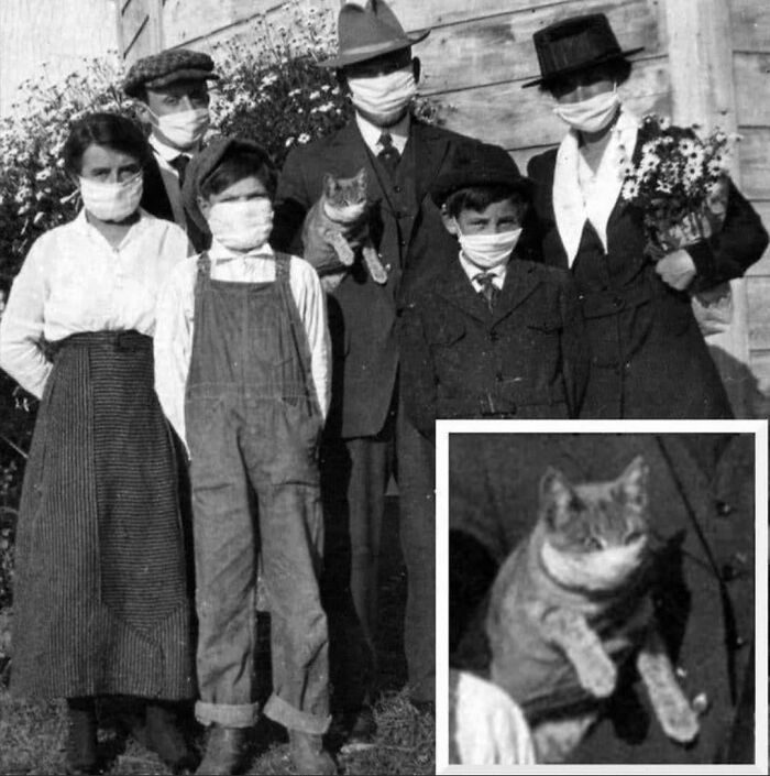 Vintage photo of a masked family posing with a cat, showcasing early 20th-century history cool kids fashion.
