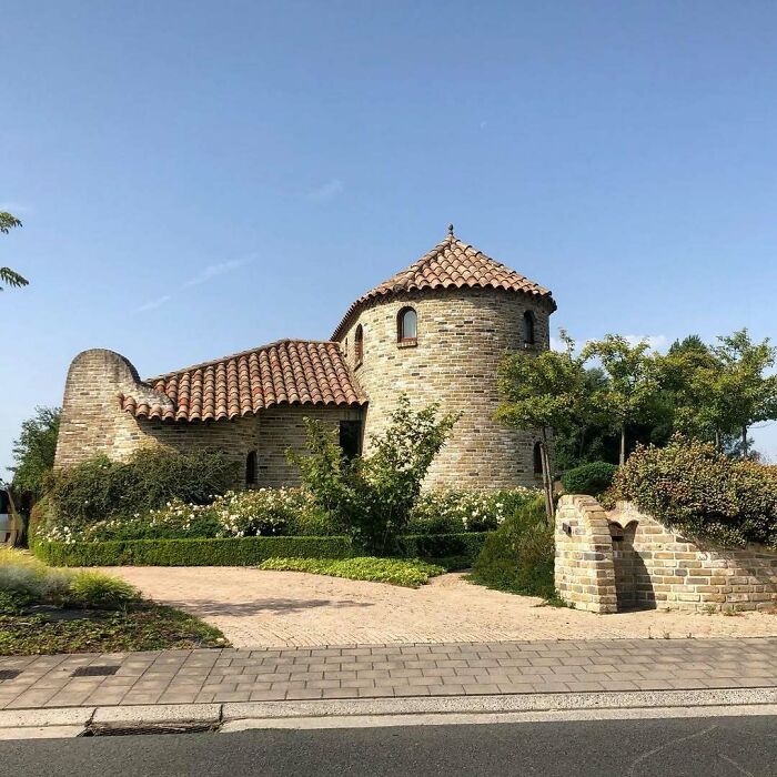 Quirky brick house with round tower and unique design, showcasing hilariously bad architecture.