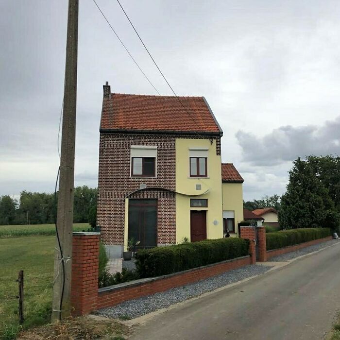 Quirky house design with mismatched brick and plaster facade on a quiet street.
