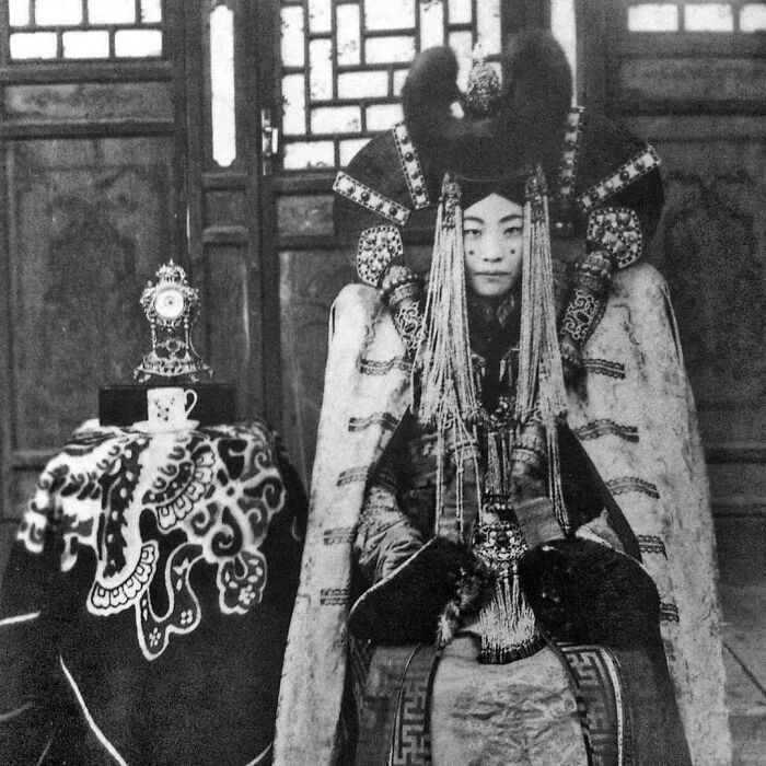 Asian historical figure in elaborate attire, seated beside a decorative table, illustrating cool kids from history.