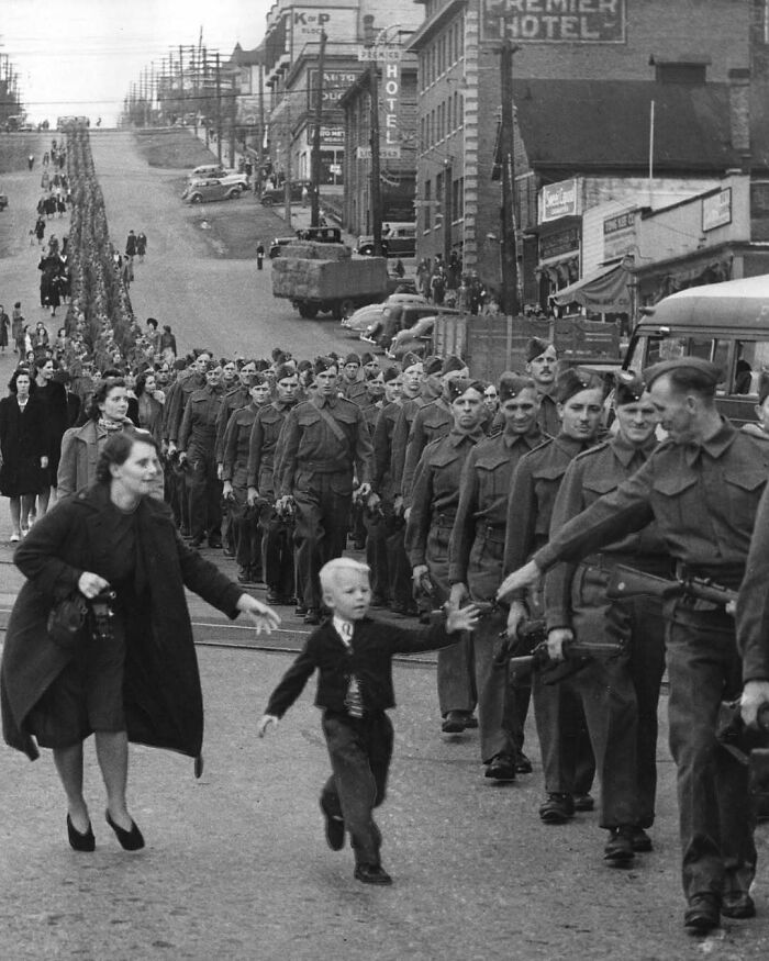 Mother and child run toward soldiers in historic scene, capturing a moment of emotion from the past.