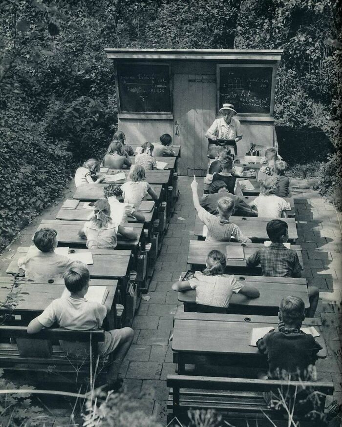 Children learning outdoors with a teacher, in a vintage classroom setting, embodying "History Cool Kids".