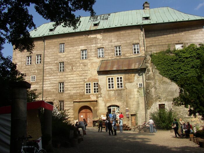Old stone building with people gathered outside, related to weird unsolved mysteries.