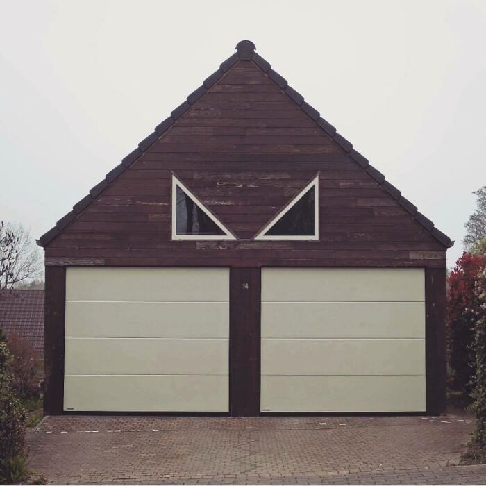 Bad house design with a garage door shaped like a face, featuring triangular windows above two garage doors.