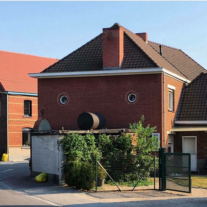 A hilariously bad house with windows resembling eyes and a pipe like a nose on a brick facade.