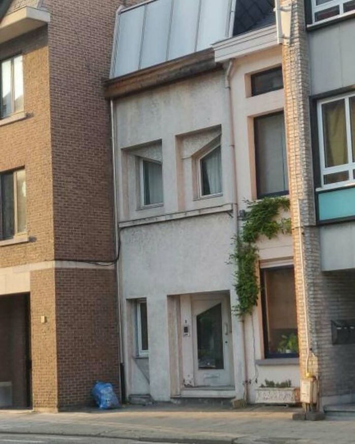 Humorously bad house with mismatched windows and uneven design in Belgium.