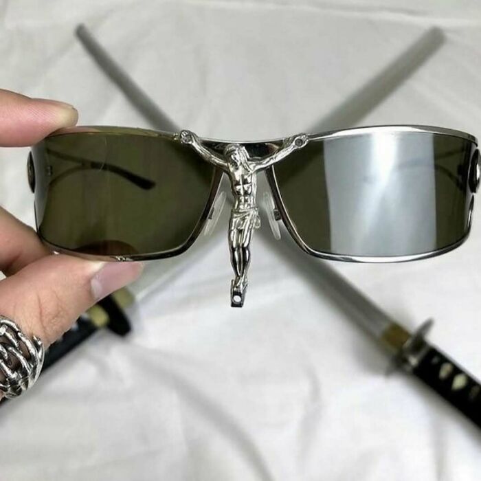 Sunglasses with a crucifix decoration in the center, held over crossed swords, creating a confusing and funny visual effect.