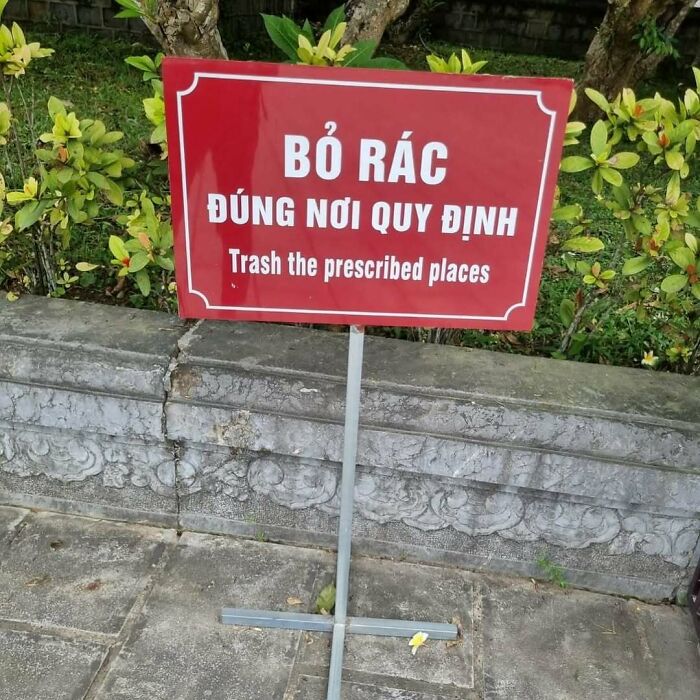 Unique garden with a humorous sign reading "Trash the prescribed places" in a lush setting.