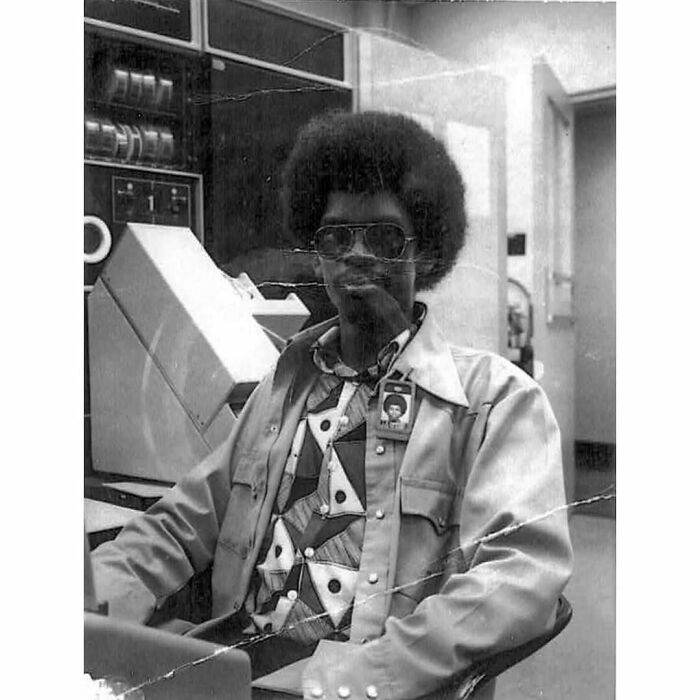 Person with afro and sunglasses in a retro tech setting, embodying the "History Cool Kids" vibe.