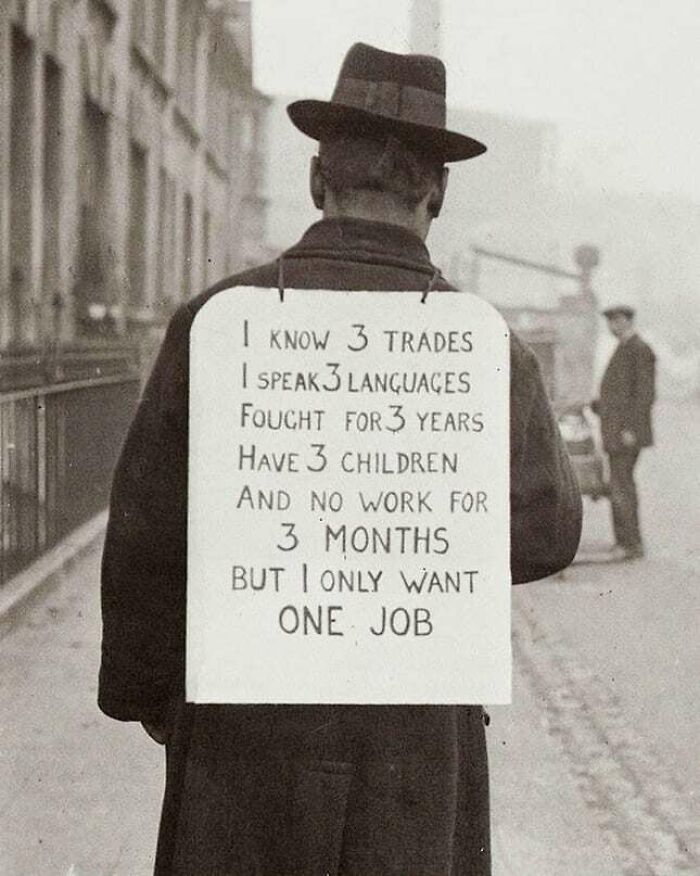 Man in vintage attire holds sign about job skills and unemployment, representing "History Cool Kids."