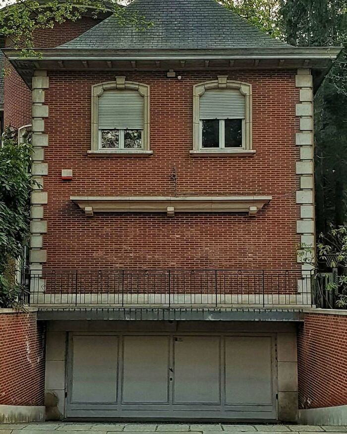 Brick house with shutters resembling eyes, creating a hilariously bad house face expression.