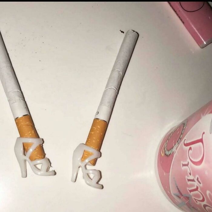 Two cigarettes with tiny high heel shoes at the ends creating a confusing and funny photo.