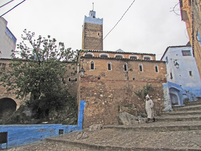 Ancient tower with stone walls and a person in traditional attire in a historical setting, highlighting overlooked historical events.