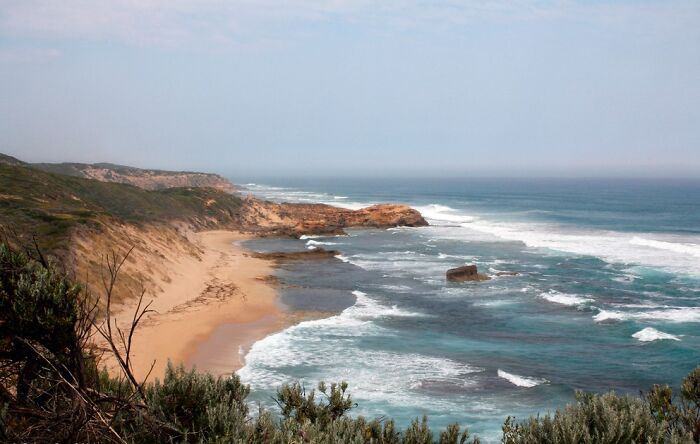 Coastal landscape potentially linked to weird unsolved mysteries, featuring rugged cliffs and the ocean meeting the sandy shore.