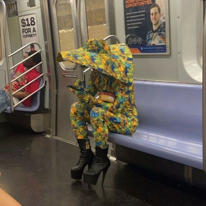 New York local in vibrant, abstract outfit with matching hat and high heels on subway, embracing experimental fashion.
