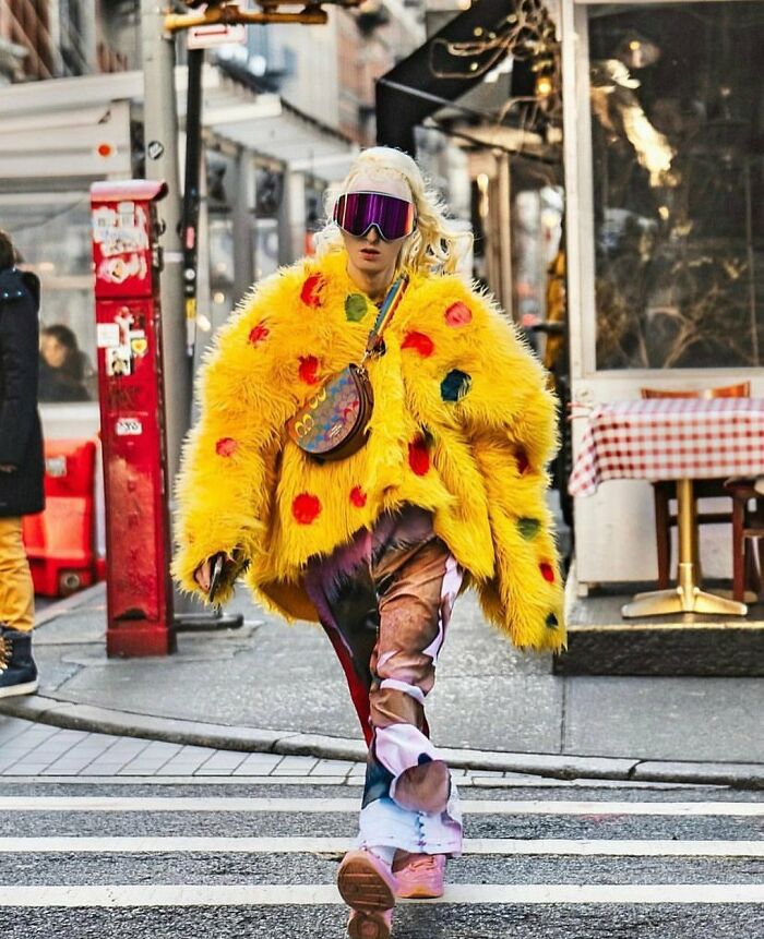 NYC local in vibrant fashion with a yellow fur coat and colorful pants, showcasing street style creativity.