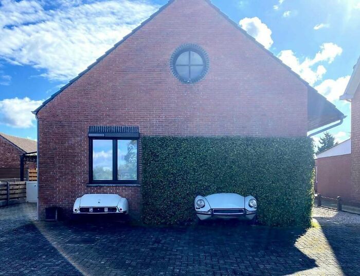 Bad house design with car fronts embedded in a brick wall, highlighting poor architectural choices.