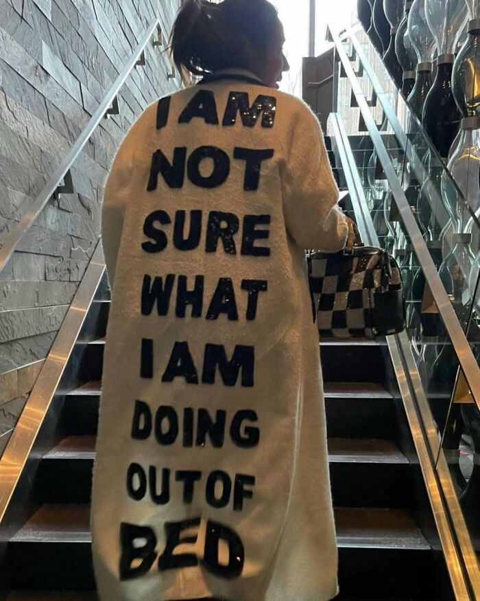 NYC local in an experimental fashion coat with bold text walking up stairs.
