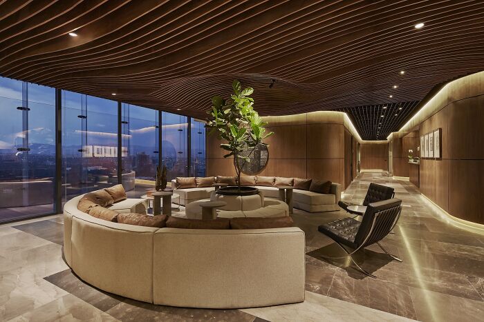 Modern interior design featuring a circular sofa, elegant lighting, and large windows with city views.