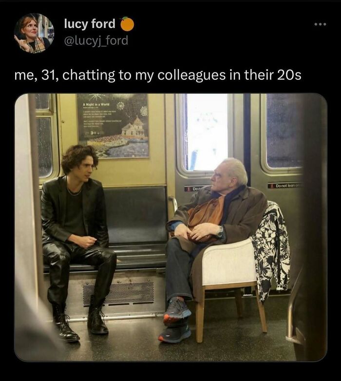 Young person in black talks to an older colleague in an office-like setting, humorously depicting office work dynamics.