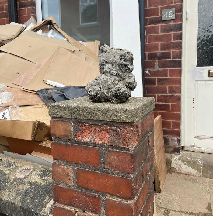 Unique garden feature atop brick pillar, surrounded by boxes and packages by a front door.